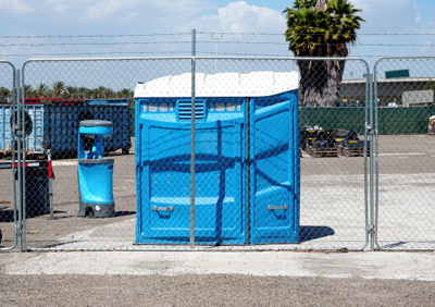 ada wheel chair accessible porta potty in a fenced area